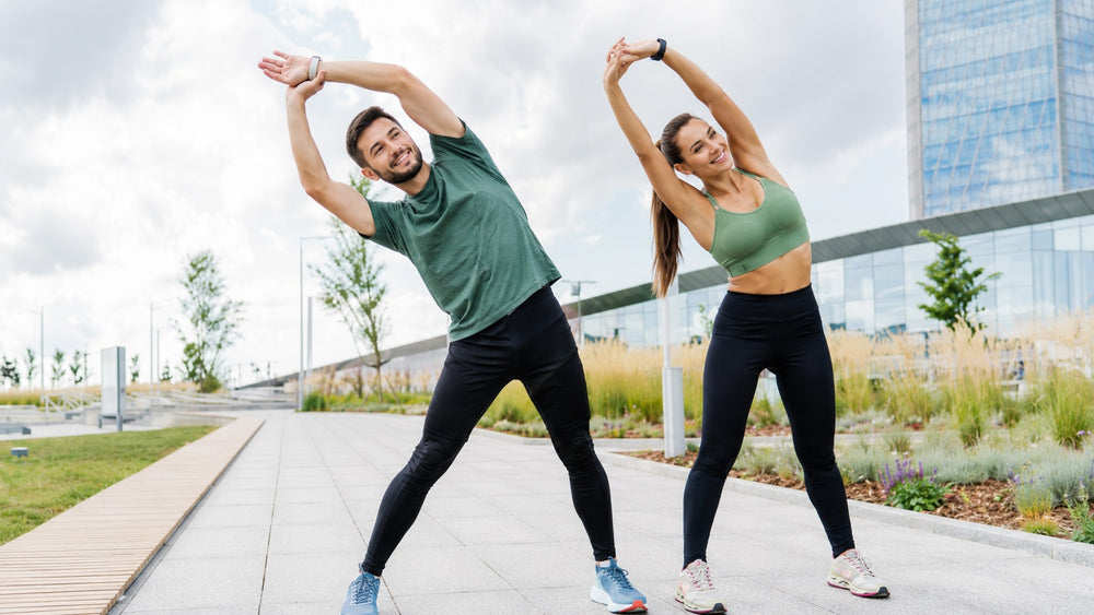 Two people stretching outdoors with a cityscape background
